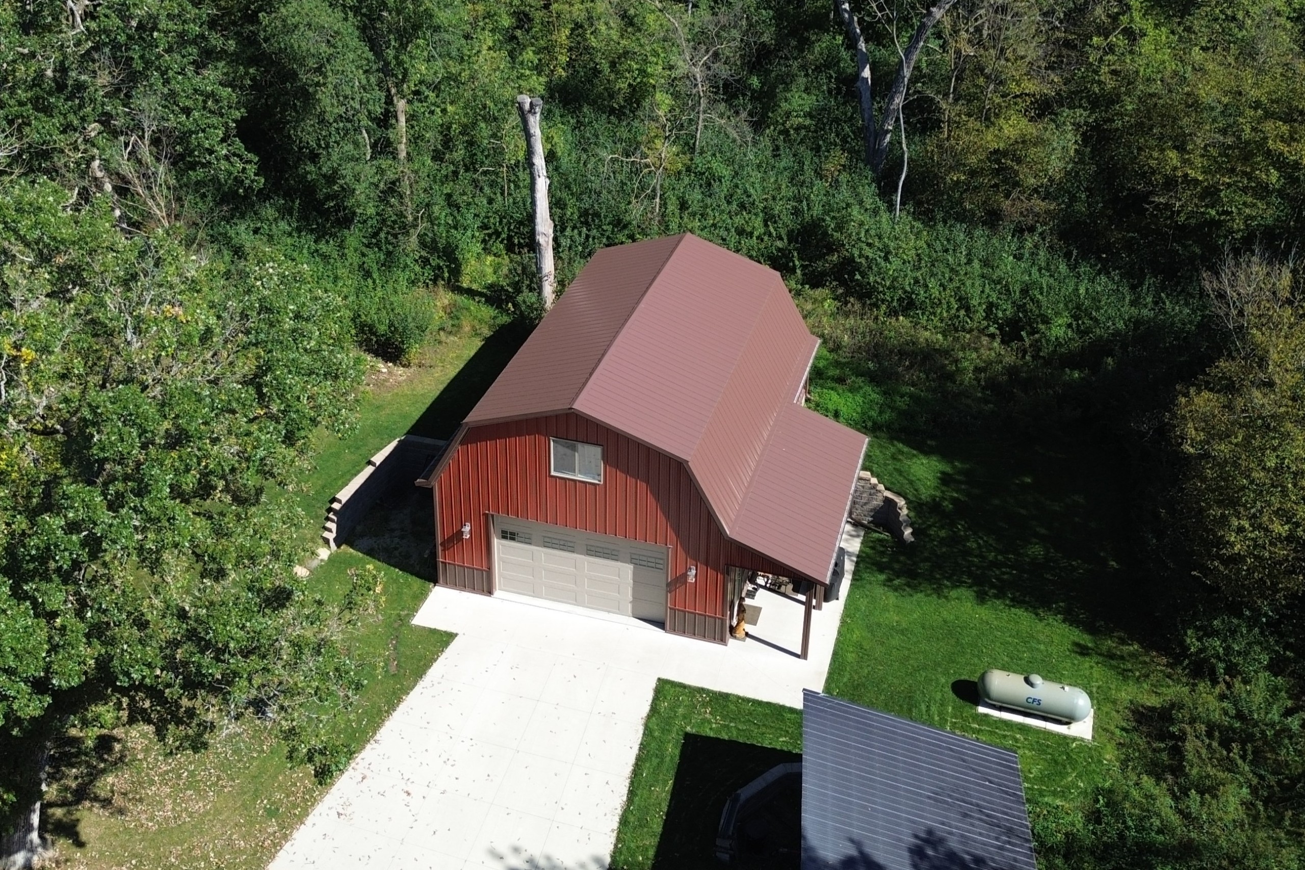Aerial view of a two-story gambrel garage with a metal roof designed to accommodate future solar panels